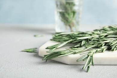 Photo of Board with fresh green rosemary twigs on table. Space for text