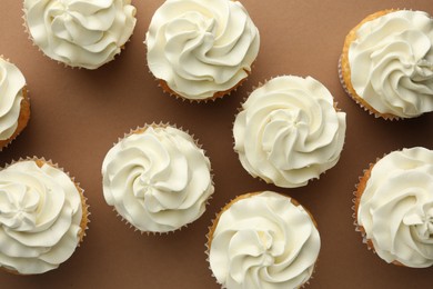 Photo of Tasty vanilla cupcakes with cream on dark beige background, top view