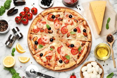 Tasty pizza with seafood and ingredients on white marble table, flat lay