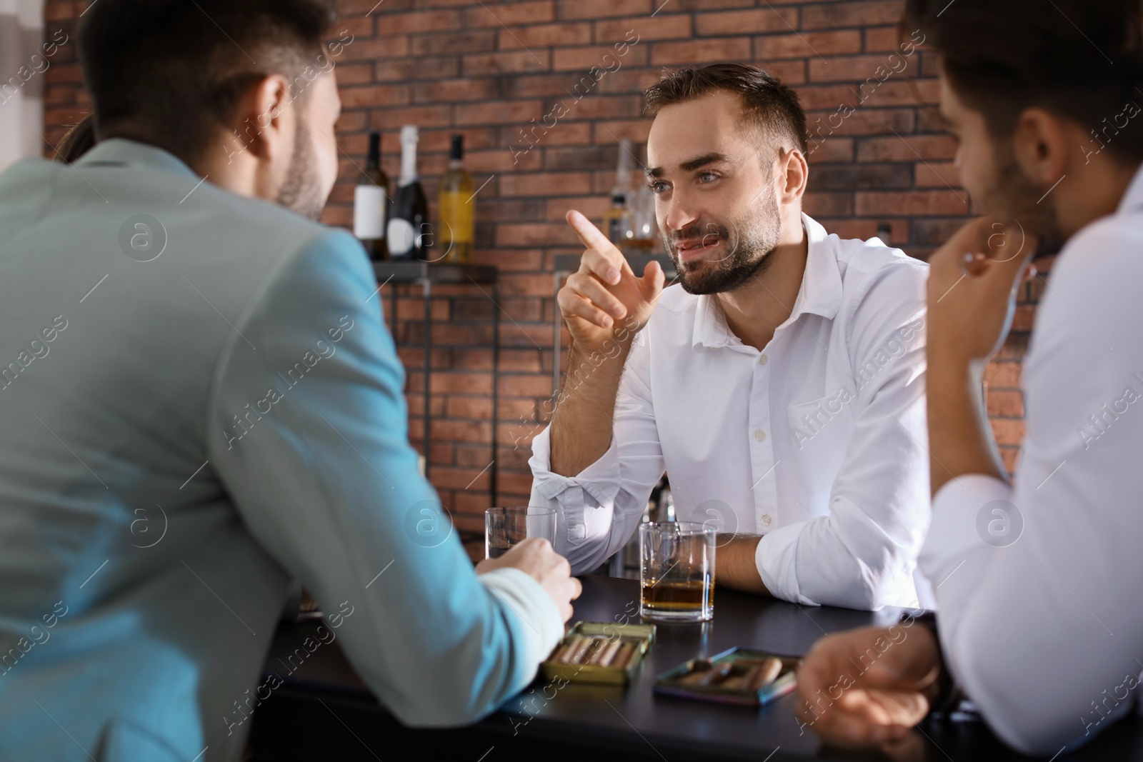 Photo of Group of friends drinking whiskey together in bar