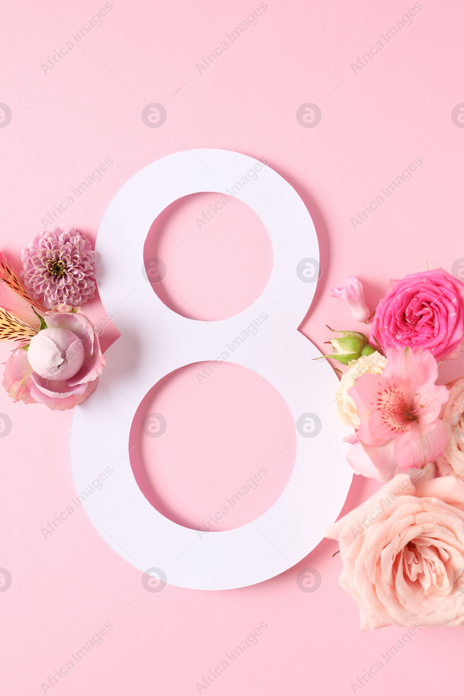 Photo of 8 March greeting card design with beautiful flowers on light pink background, top view
