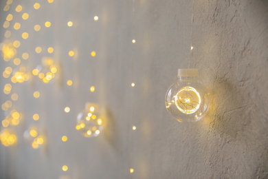 Photo of Stylish light bulb near textured white wall, space for text. Ideas for Christmas interior decoration