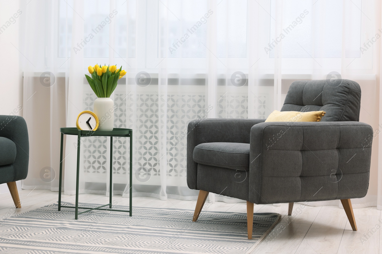 Photo of Spring atmosphere. Stylish living room interior with comfortable furniture and bouquet of beautiful yellow tulips