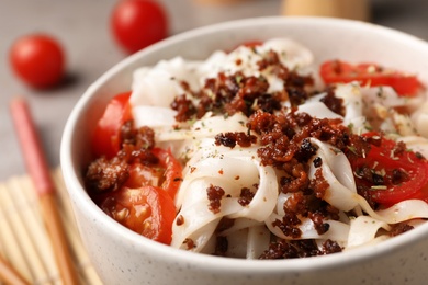 Photo of Bowl with rice noodles, meat and tomatoes, closeup