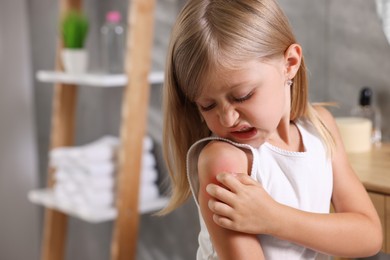 Photo of Suffering from allergy. Little girl scratching her arm in bathroom, space for text