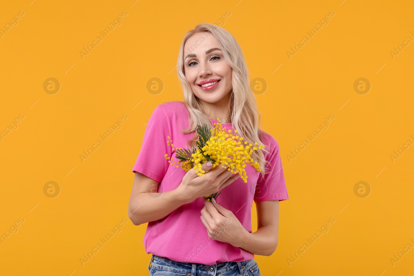 Photo of Happy young woman with beautiful bouquet on orange background