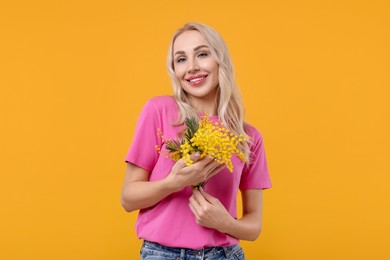 Happy young woman with beautiful bouquet on orange background