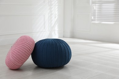 Different stylish poufs in room, space for text