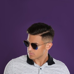 Photo of Handsome man wearing sunglasses on purple background, closeup