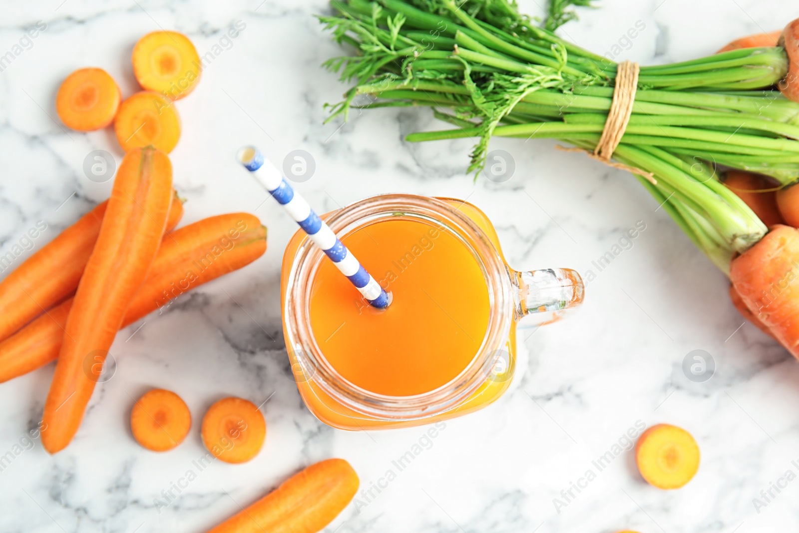 Photo of Mason jar with carrot juice and fresh vegetable on table