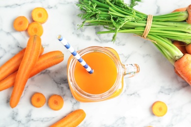 Photo of Mason jar with carrot juice and fresh vegetable on table
