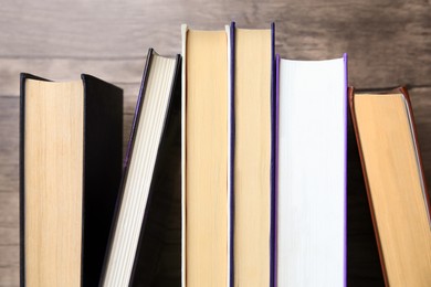 Collection of different books near wooden wall, closeup