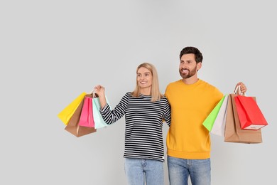 Family shopping. Happy couple with many colorful bags on light grey background. Space for text