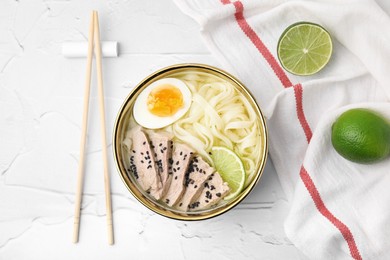 Photo of Bowl of delicious rice noodle soup with meat and egg on white textured table, flat lay