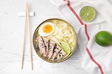 Bowl of delicious rice noodle soup with meat and egg on white textured table, flat lay