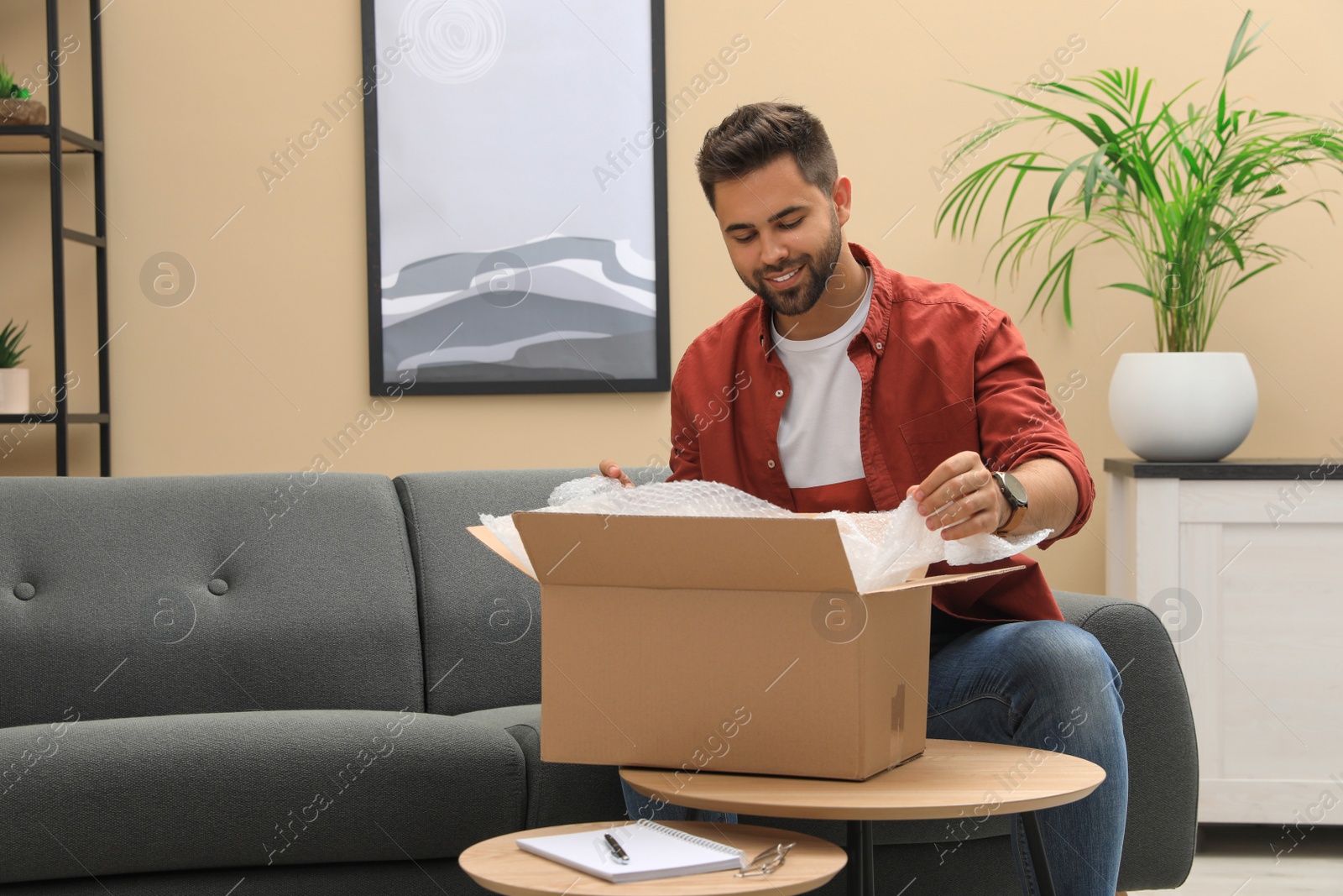 Photo of Man unpacking parcel at home. Online shopping