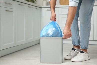 Photo of Man taking garbage bag out of bin at home, closeup