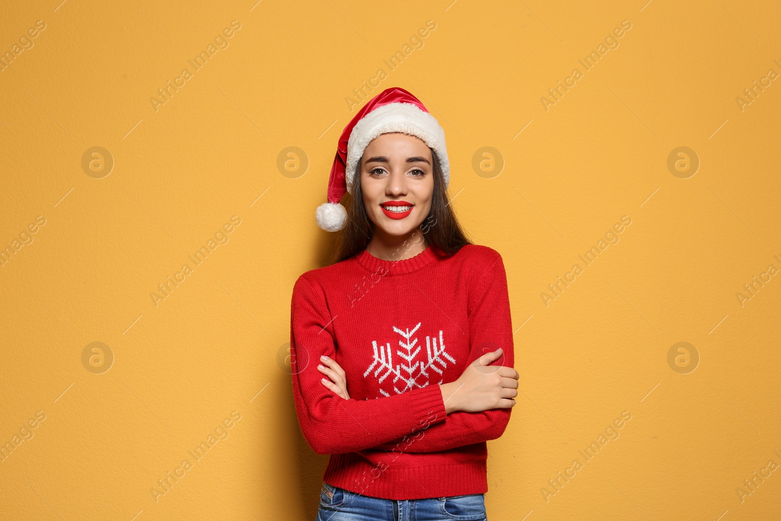 Photo of Young woman in Christmas sweater and hat on color background