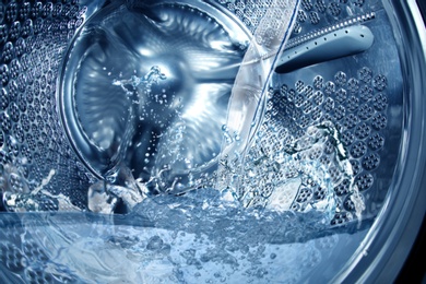 Image of Closeup view on washing machine drum filling with water 