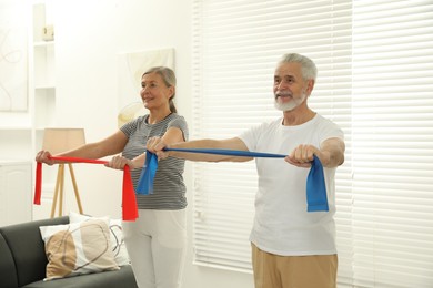 Photo of Senior couple doing exercise with fitness elastic bands at home