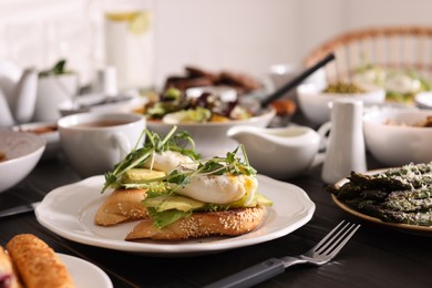 Photo of Delicious sandwiches with eggs and avocado served on buffet table for brunch