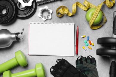 Photo of Notebook, apple and sports equipment on grey textured table, flat lay. Personal training