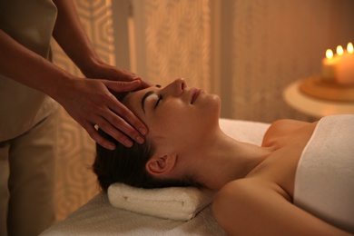 Photo of Young woman receiving head massage in spa salon