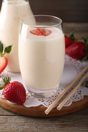 Photo of Tasty yogurt in glass, straws and strawberries on wooden table, closeup
