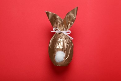 Easter bunny made of shiny gold paper on red background, top view