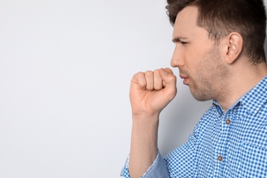 Photo of Young man coughing on light background