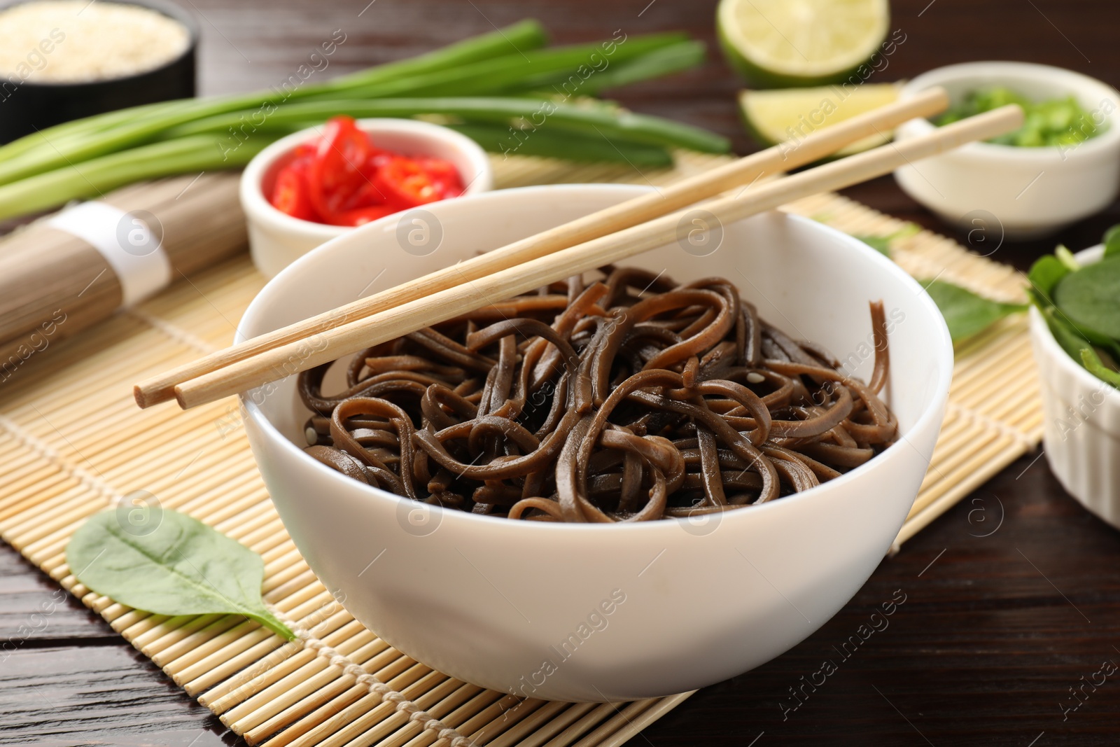 Photo of Tasty buckwheat noodles (soba) served on wooden table, closeup