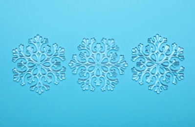 Photo of Beautiful decorative snowflakes on light blue background, flat lay