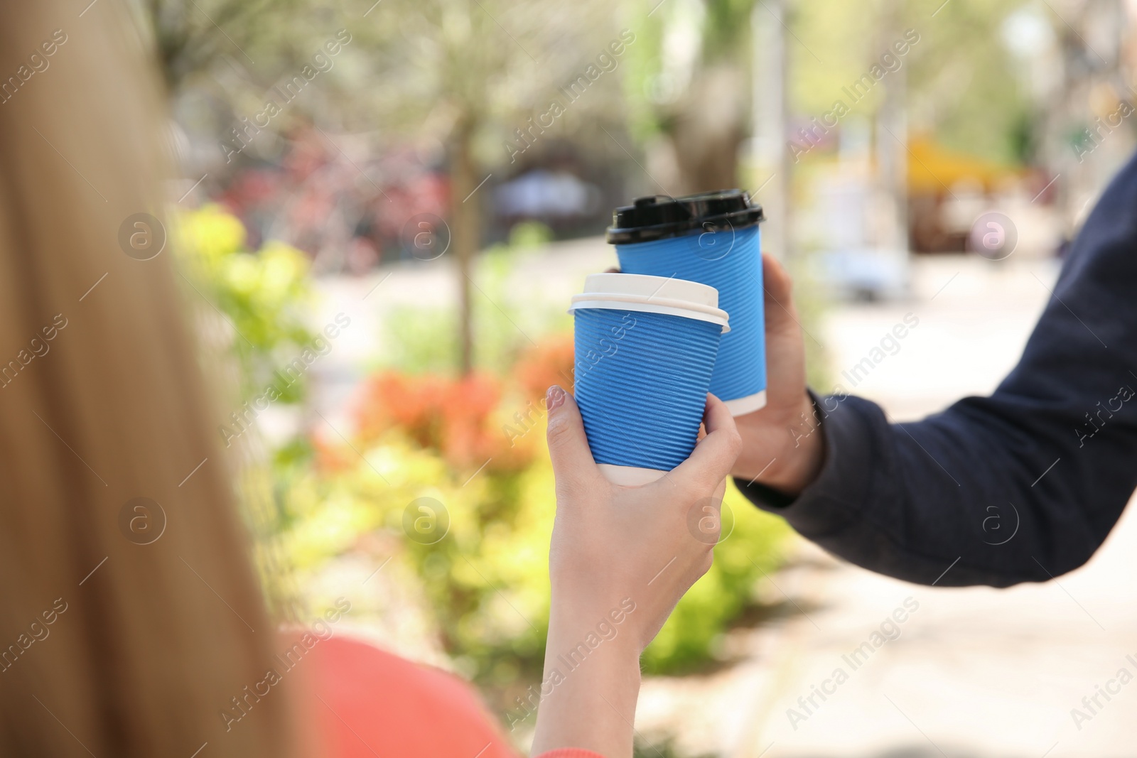 Photo of Couple with takeaway coffee cups outdoors, closeup