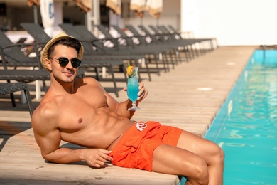 Photo of Young man with cocktail near pool on sunny day