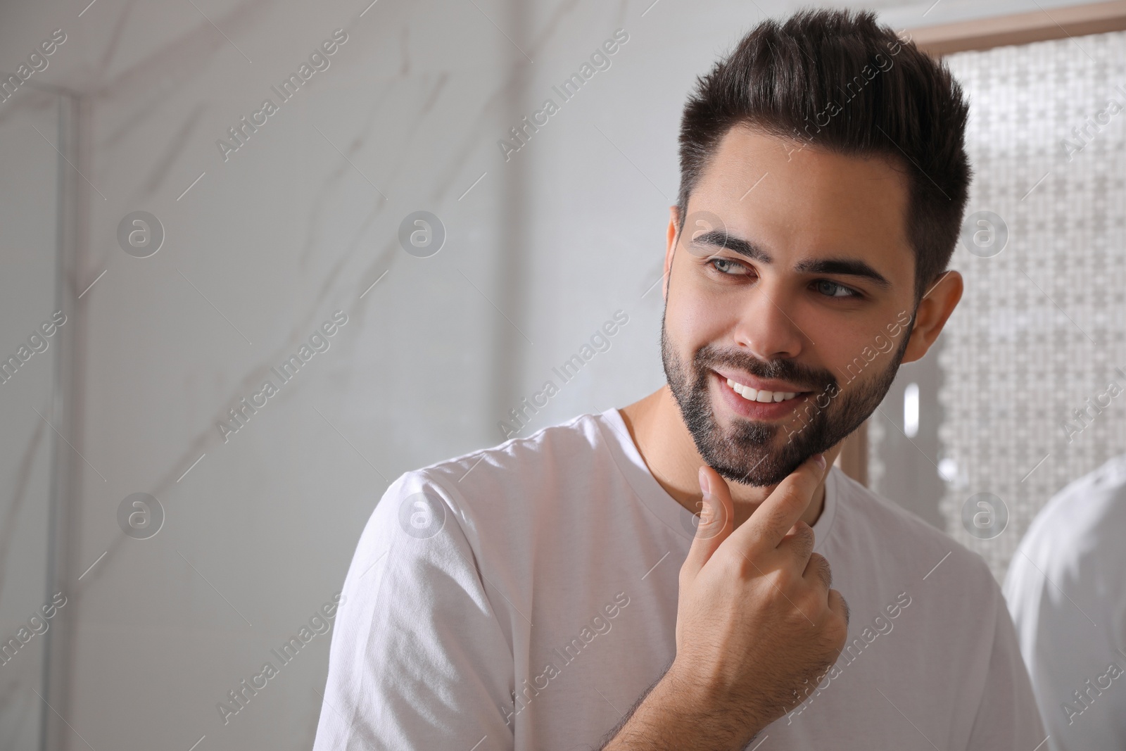 Photo of Handsome young man after shaving in bathroom, space for text