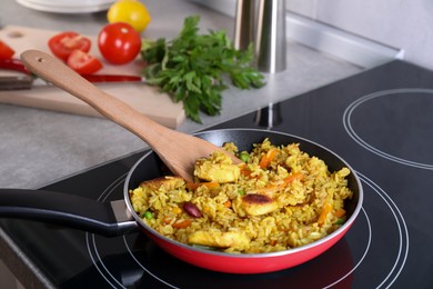 Photo of Tasty rice with meat and vegetables in frying pan on induction stove