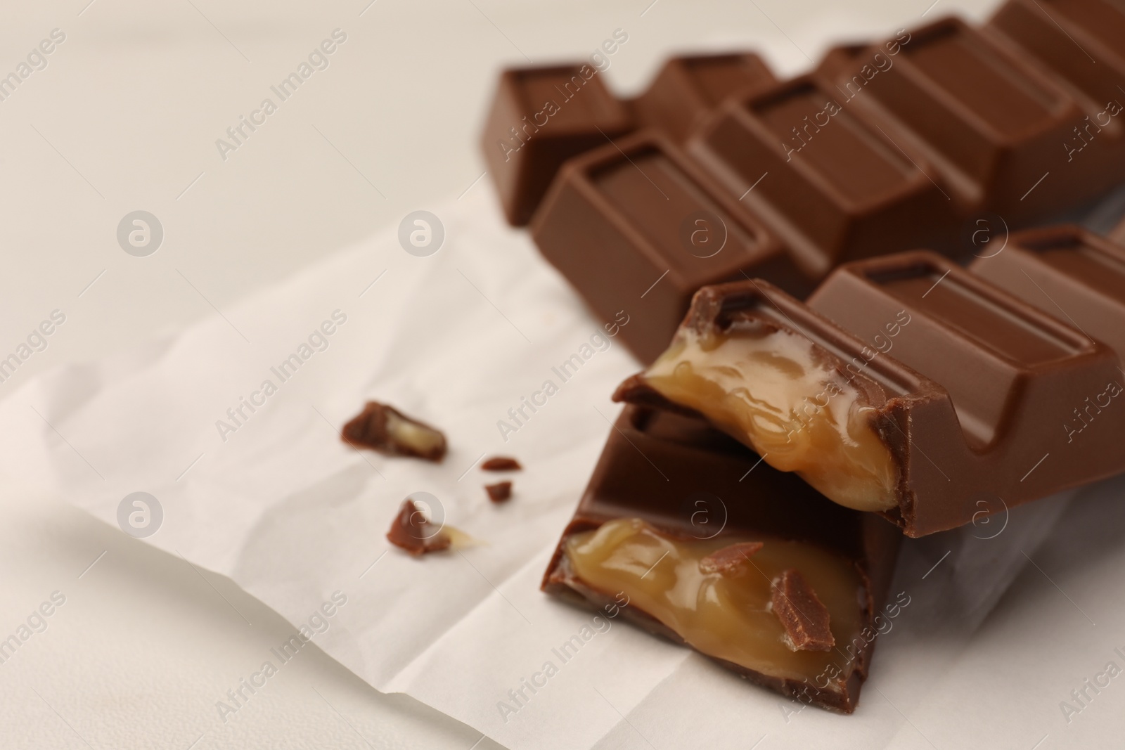 Photo of Tasty chocolate bars on white table, closeup. Space for text