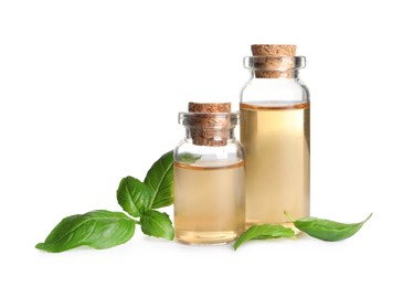 Photo of Glass bottles of basil essential oil and leaves on white background