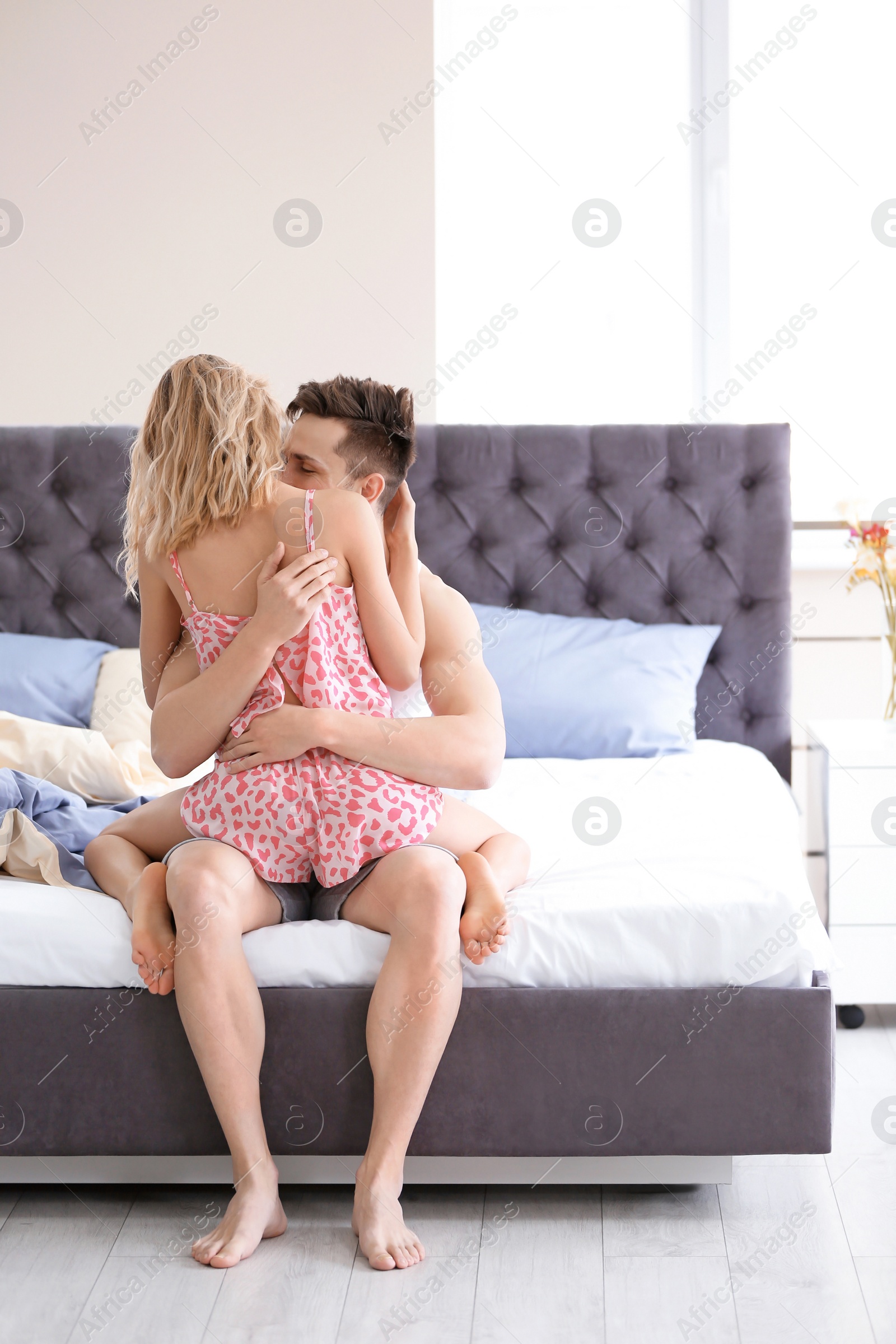 Photo of Happy young couple being intimate on bed at home