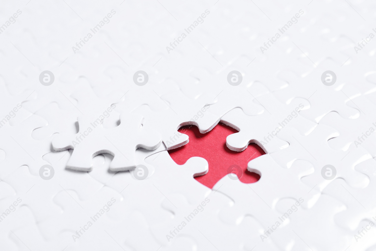 Photo of Blank white puzzle with separated piece on red background