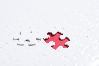 Photo of Blank white puzzle with separated piece on red background