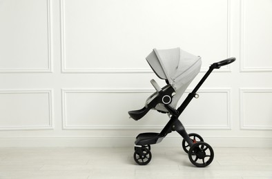 Photo of Baby carriage. Modern pram near white wall, space for text