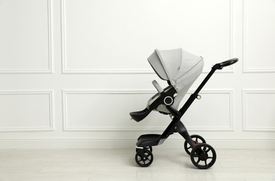 Baby carriage. Modern pram near white wall, space for text