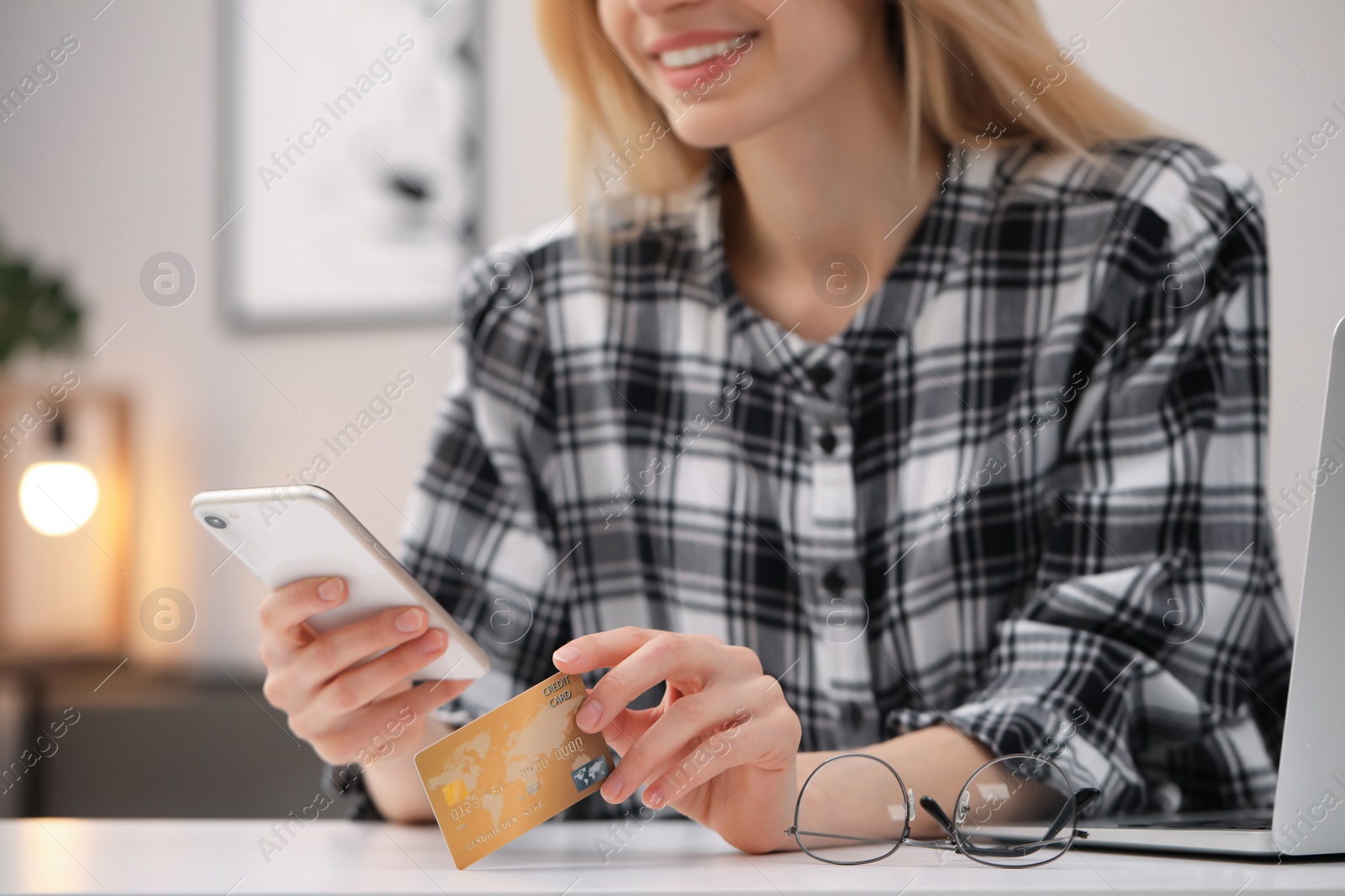 Photo of Woman with credit card using smartphone for online shopping at white table, closeup