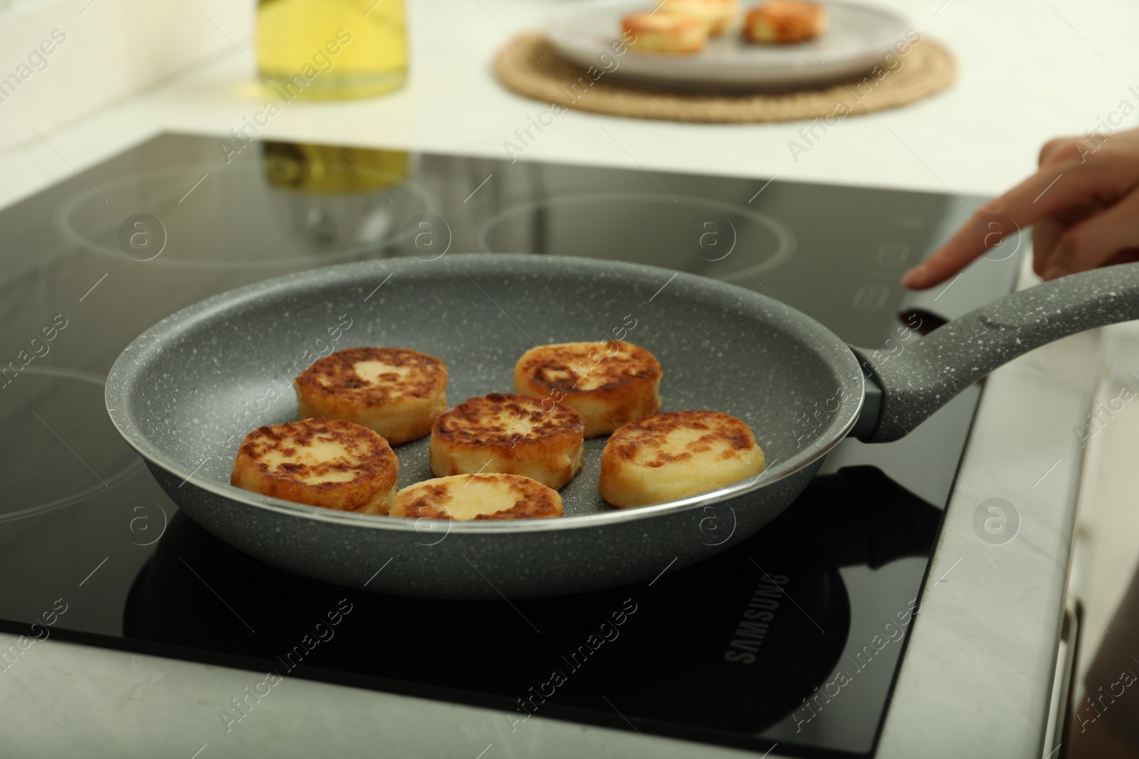 Photo of Woman frying delicious cottage cheese pancakes in kitchen, closeup