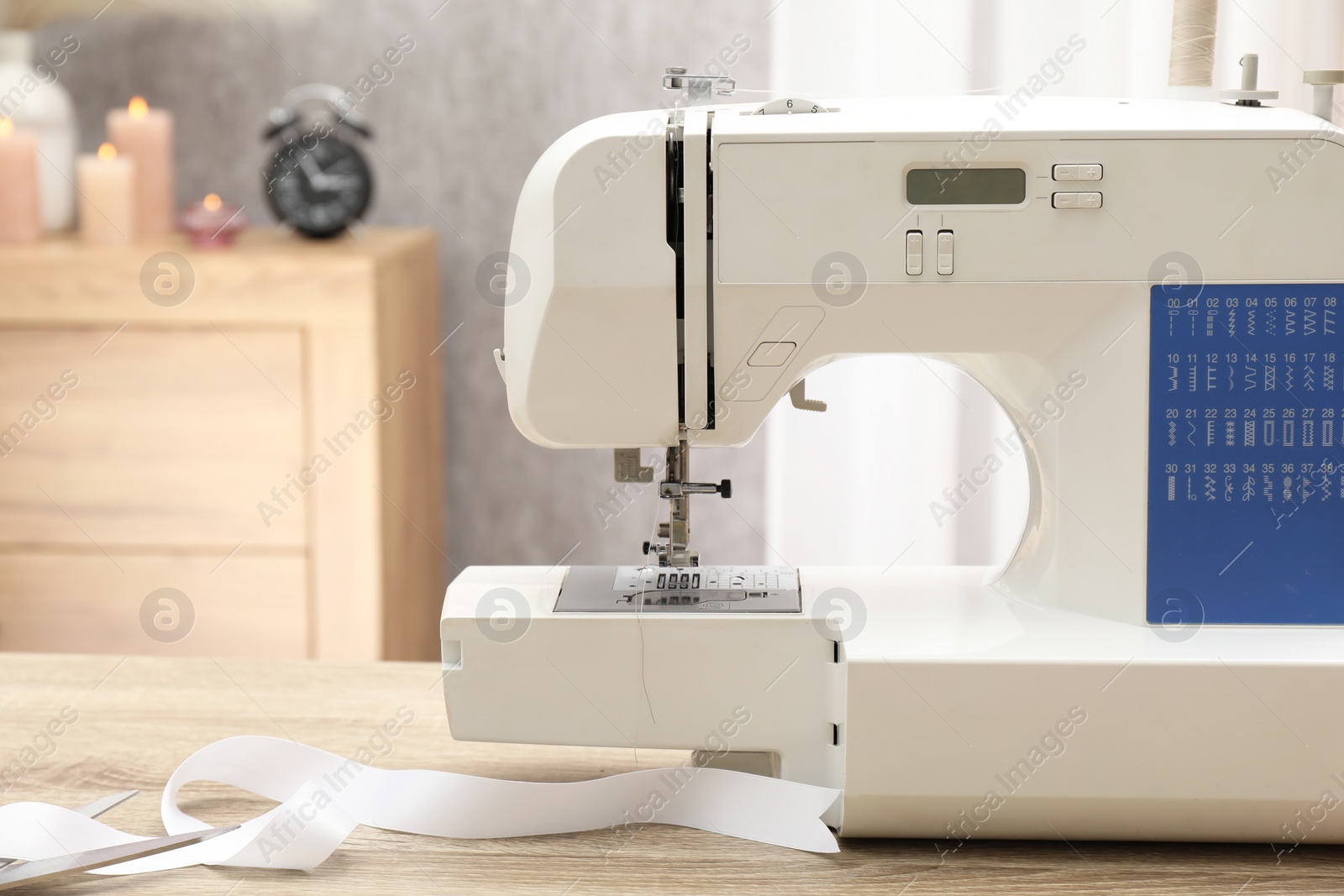 Photo of White sewing machine on wooden table indoors