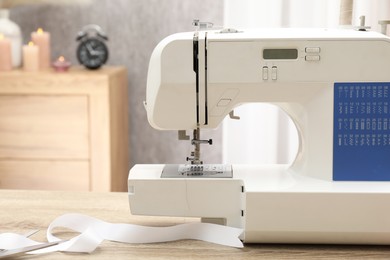 Photo of White sewing machine on wooden table indoors