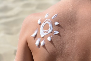 Sun drawn with sunscreen on child's back at beach, closeup