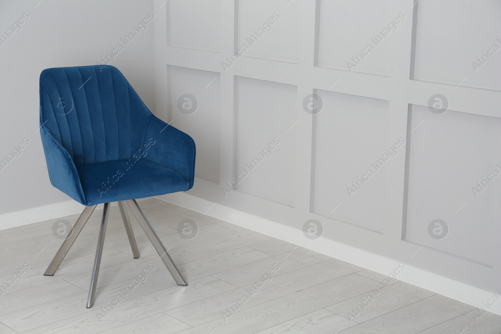 Photo of Stylish blue armchair near light wall in room. Space for text
