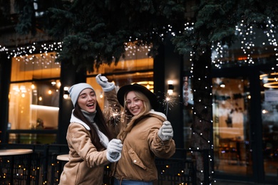 Photo of Happy young women with sparklers at winter fair